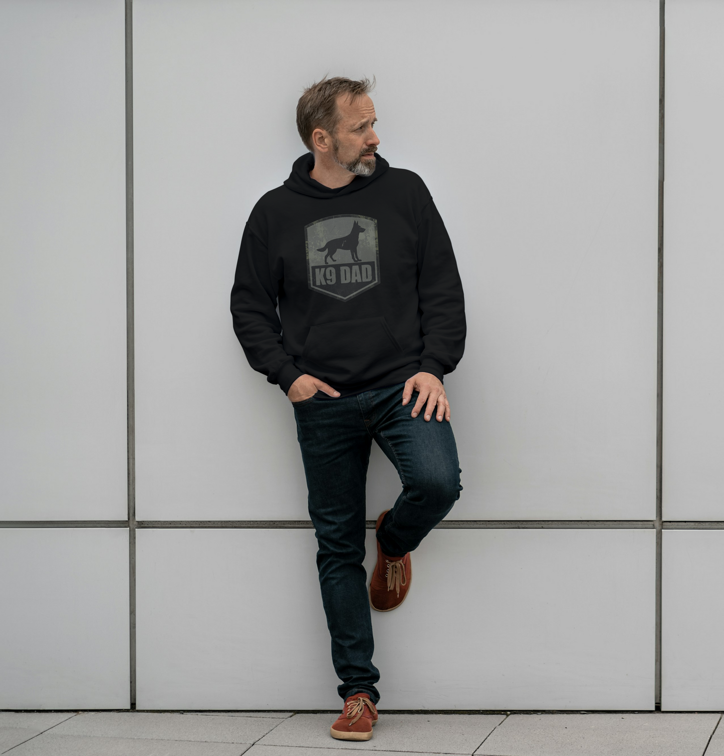 Man wearing a black hoodie with a 'Dog Dad' graphic against a light gray tiled wall.